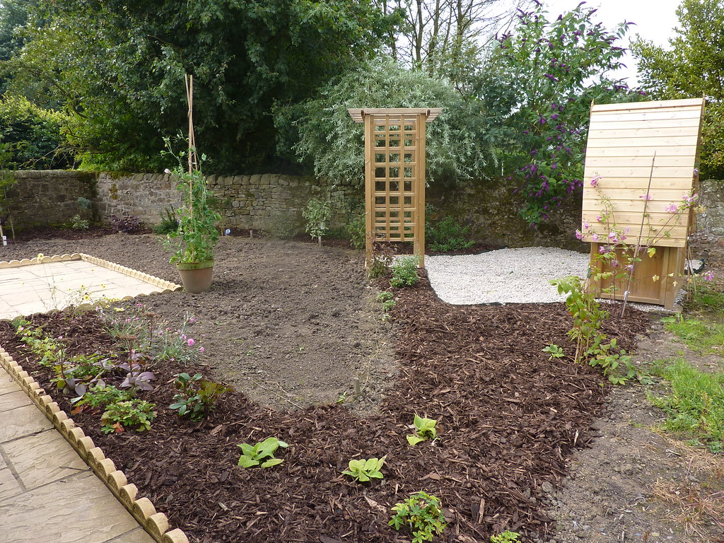 Fresh bark mulch spread around new plantings in a landscaped garden bed